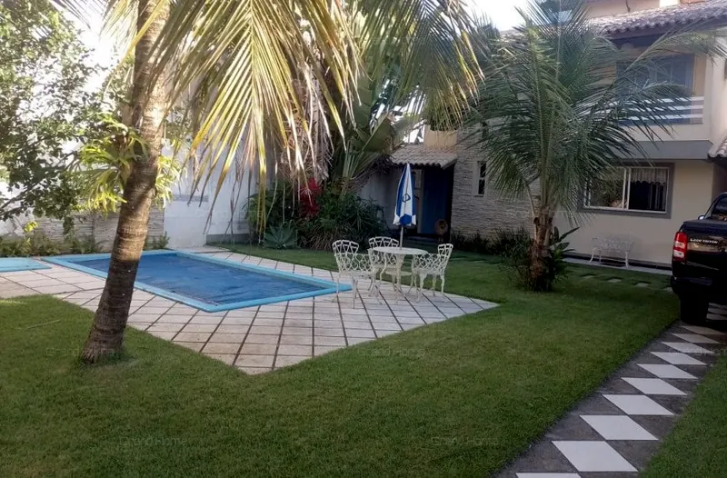 Jardim com piscina e coqueiros em frente à casa