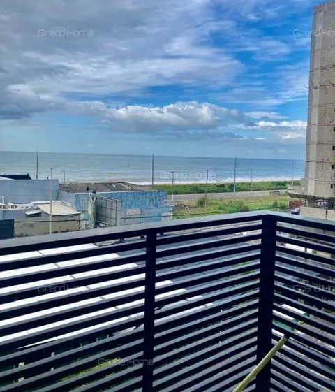 Varanda com guarda-corpo de ripas e vista para o mar