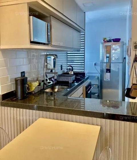 Cozinha com bancada escura, armários claros e geladeira inox