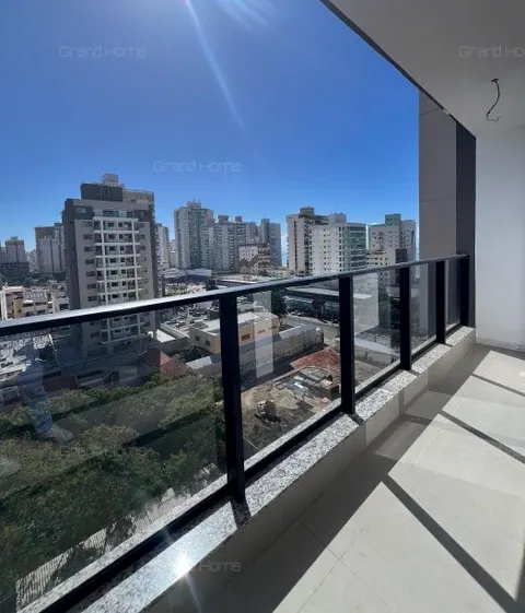 Varanda com guarda-corpo de vidro e vista para os prédios do bairro