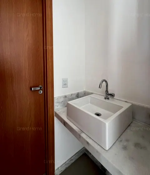 Banheiro com cuba branca sobre bancada de pedra clara