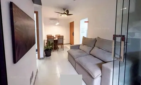 Sala com sofá cinza, ventilador de teto e mesa de jantar ao fundo