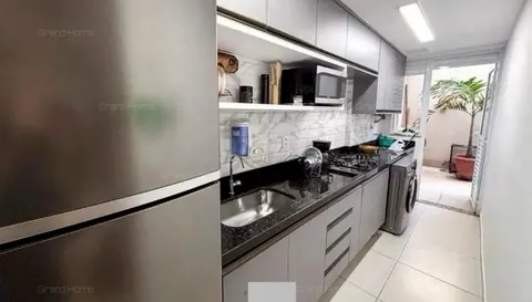 Cozinha com armários cinza, bancada de granito e área de serviço ao fundo